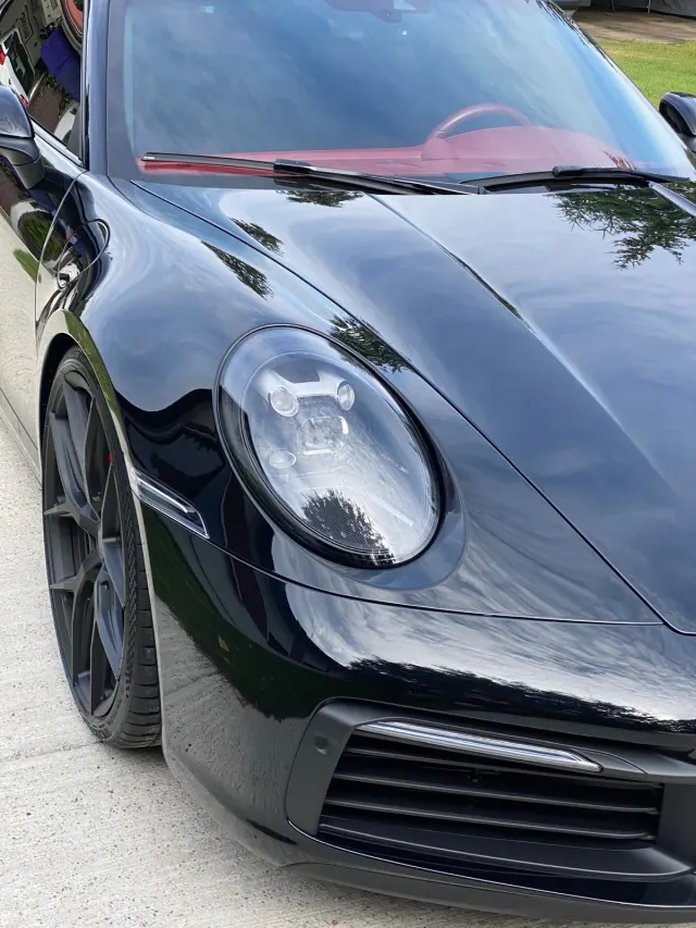Headlight and glossy bonnet of a black Porsche 911