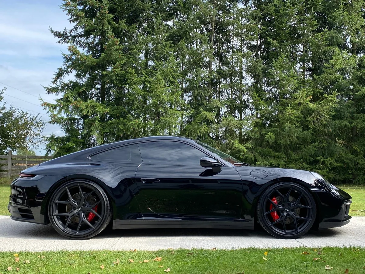 Black Porsche 911 in profile, with paint reflections and red brake calipers
