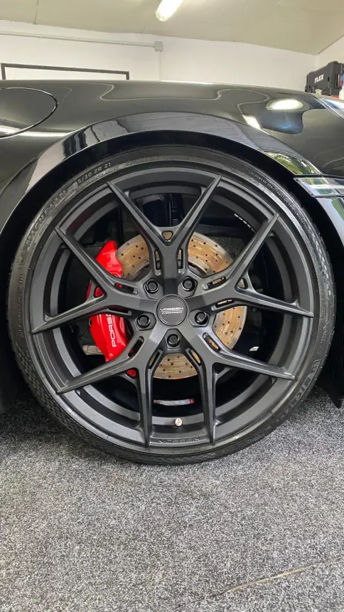 Dark Porsche wheel and red brake caliper
